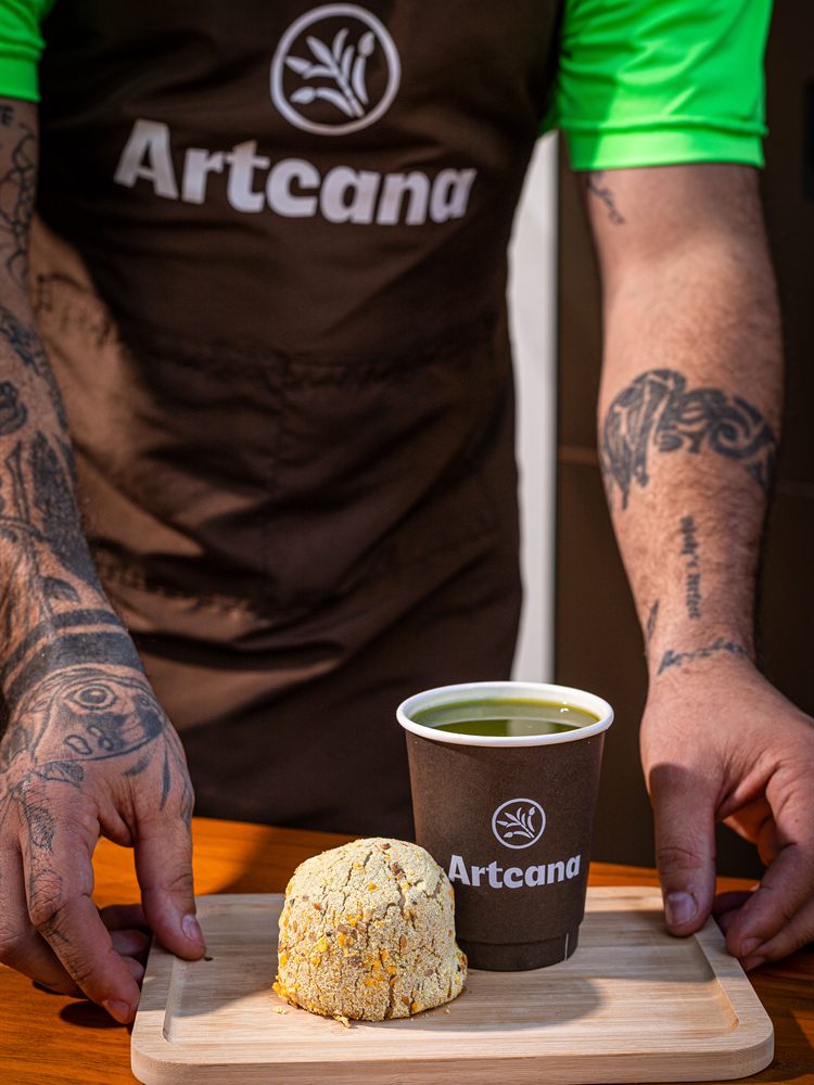 Atendente Artcana servindo caldo de cana e coxinha fit